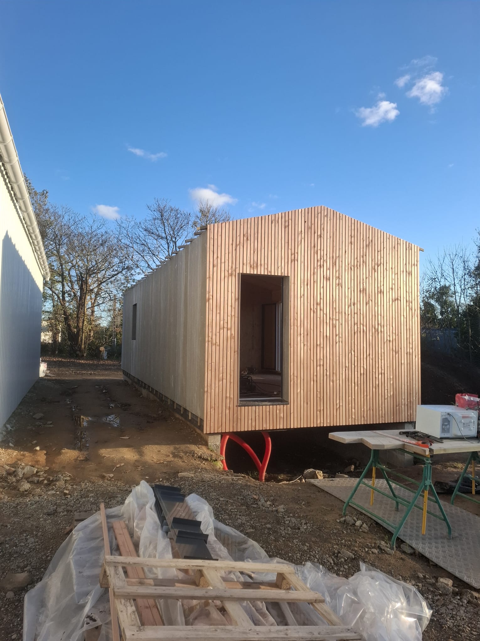 Bureaux à ossature bois, pignon en bardage bois vertical et grande baie vitrée
