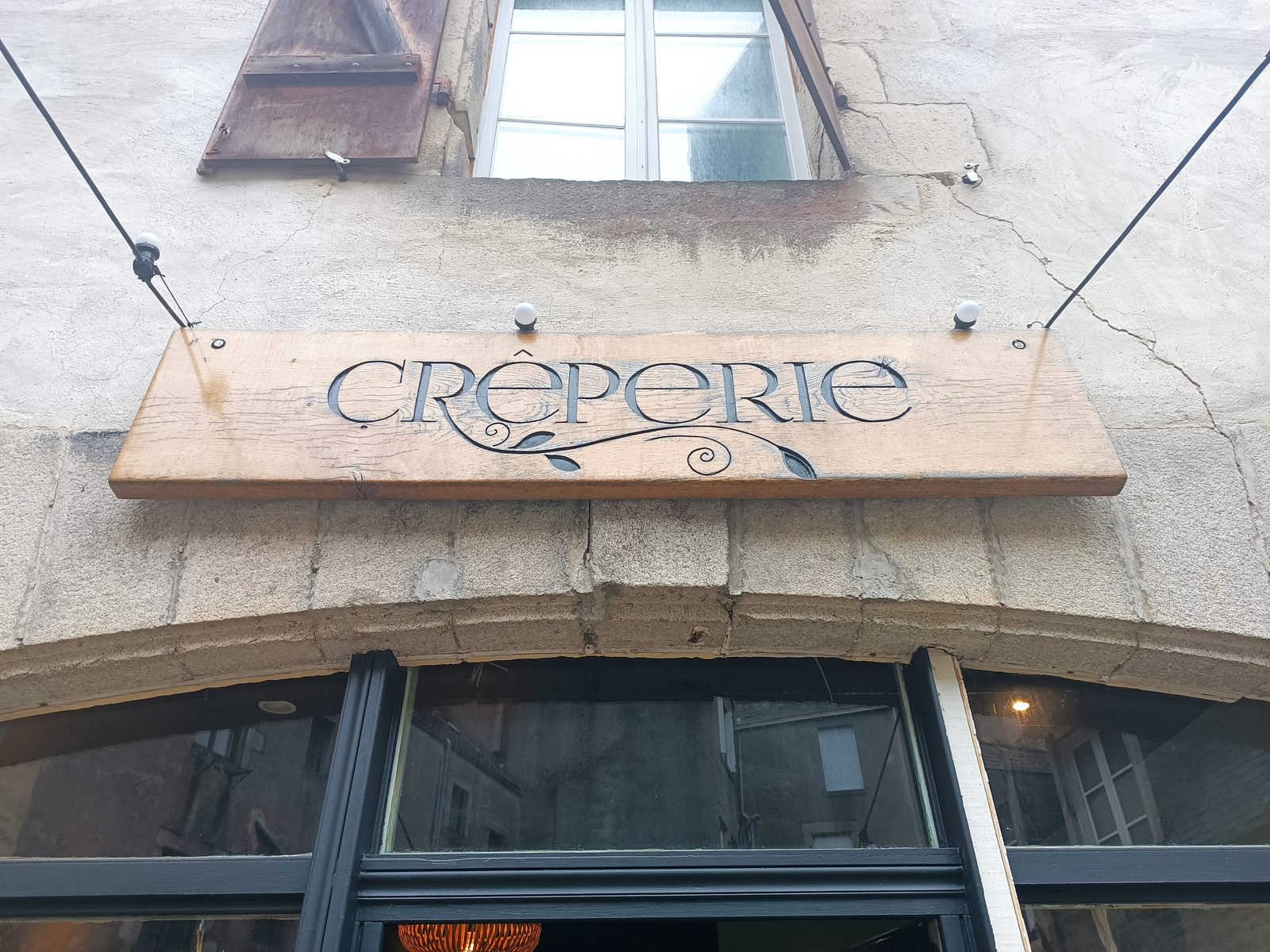 Enseigne en bois gravée « Crêperie » avec motif décoratif, en gros plan