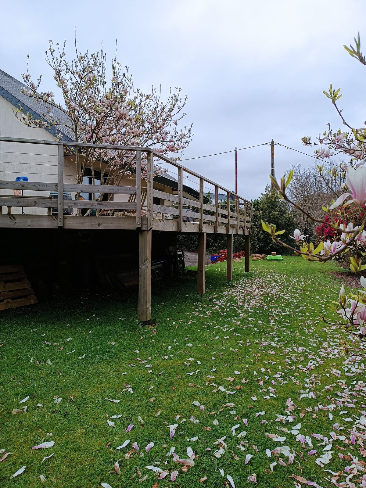 Terrasse surélevée sur pilotis vue depuis le jardin, structure portée par des poteaux