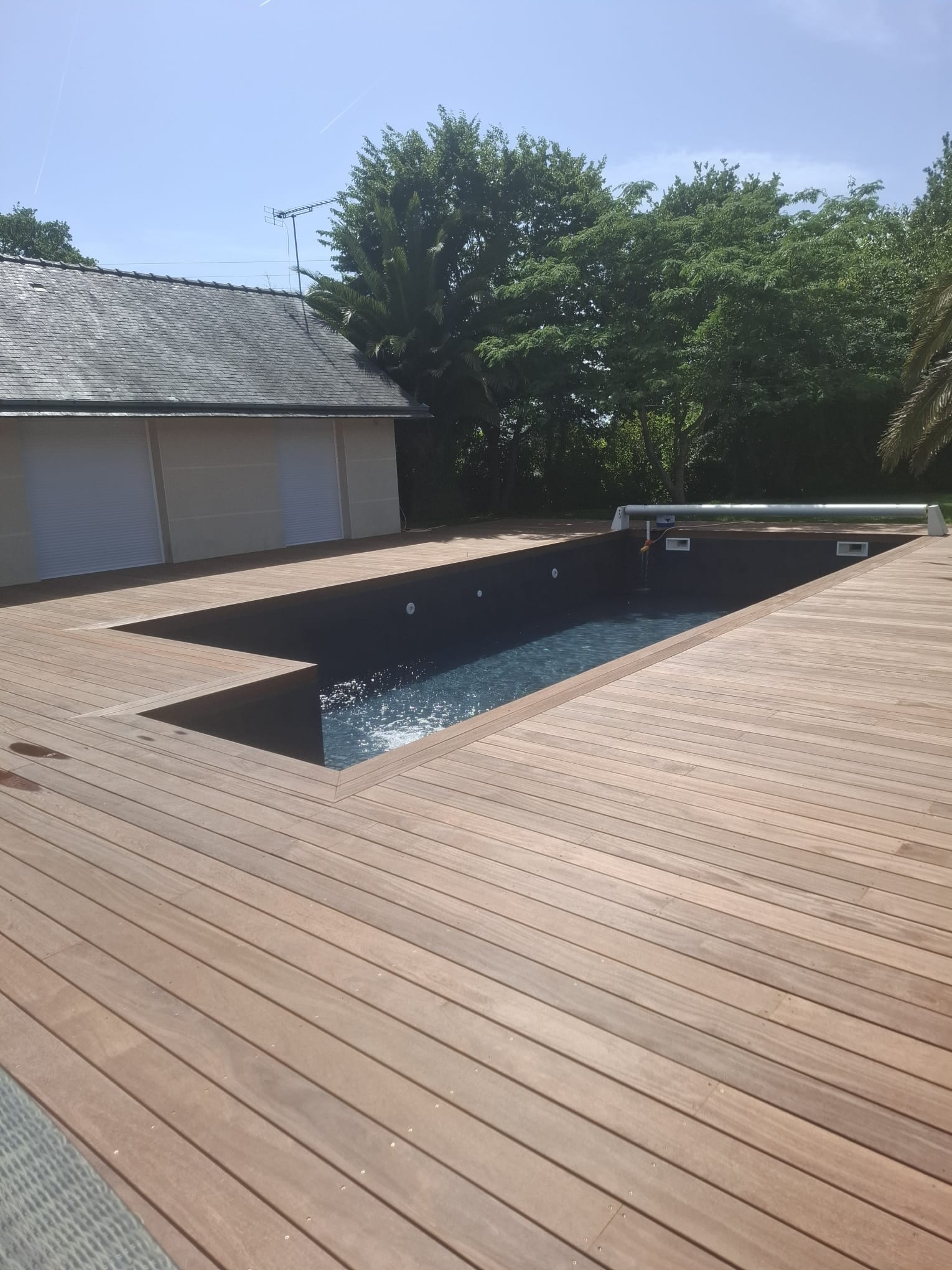 Vue d'ensemble de la terrasse en Cumaru épousant les rebords de la piscine